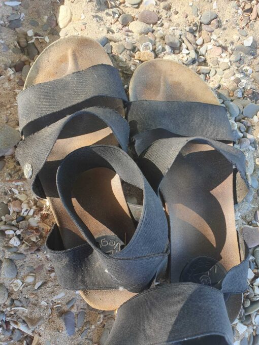 schwarze, vegane, lang getragene und verschwitzte Sandalen